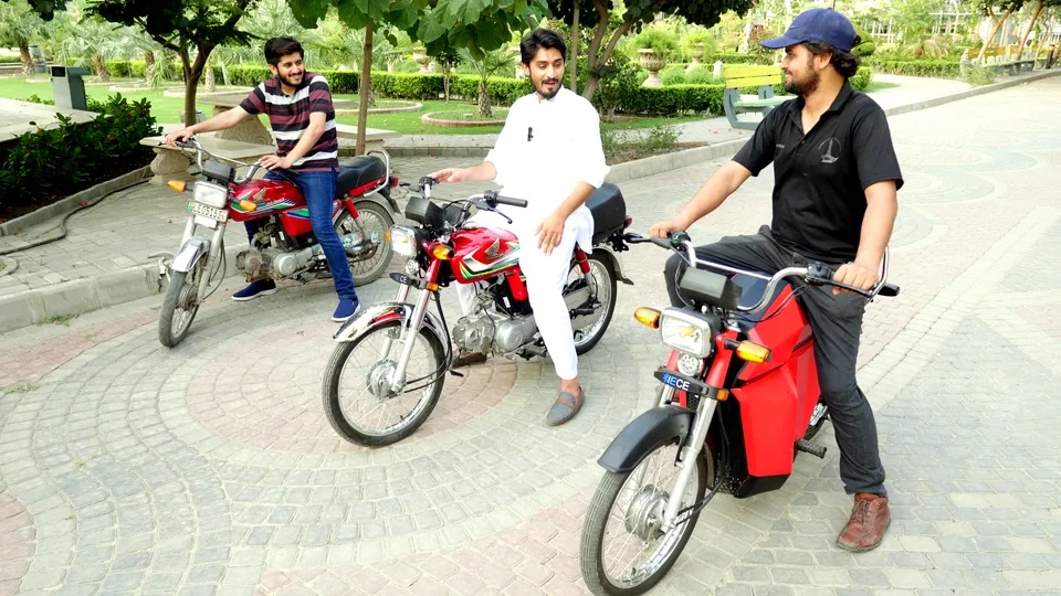 Riders on SAHER-retrofitted motorcycles alongside a standard 70cc motorcycle
